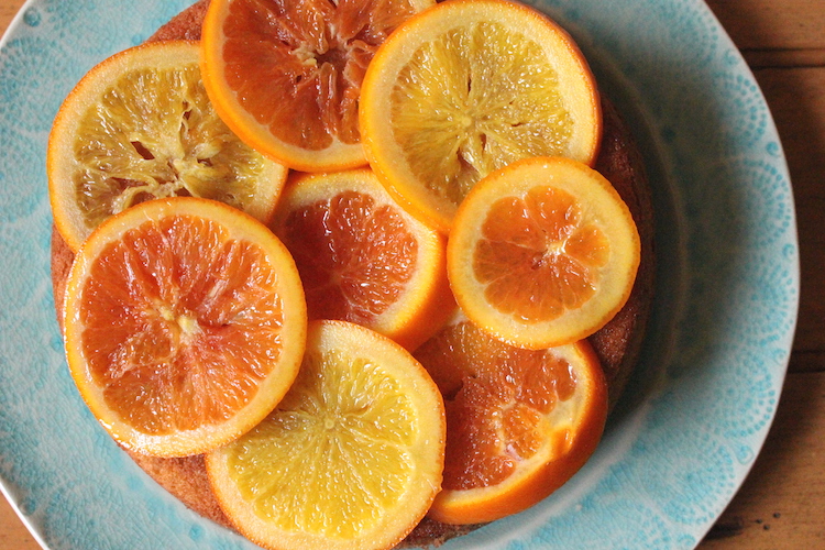 An olive oil cake topped with different color candied oranges